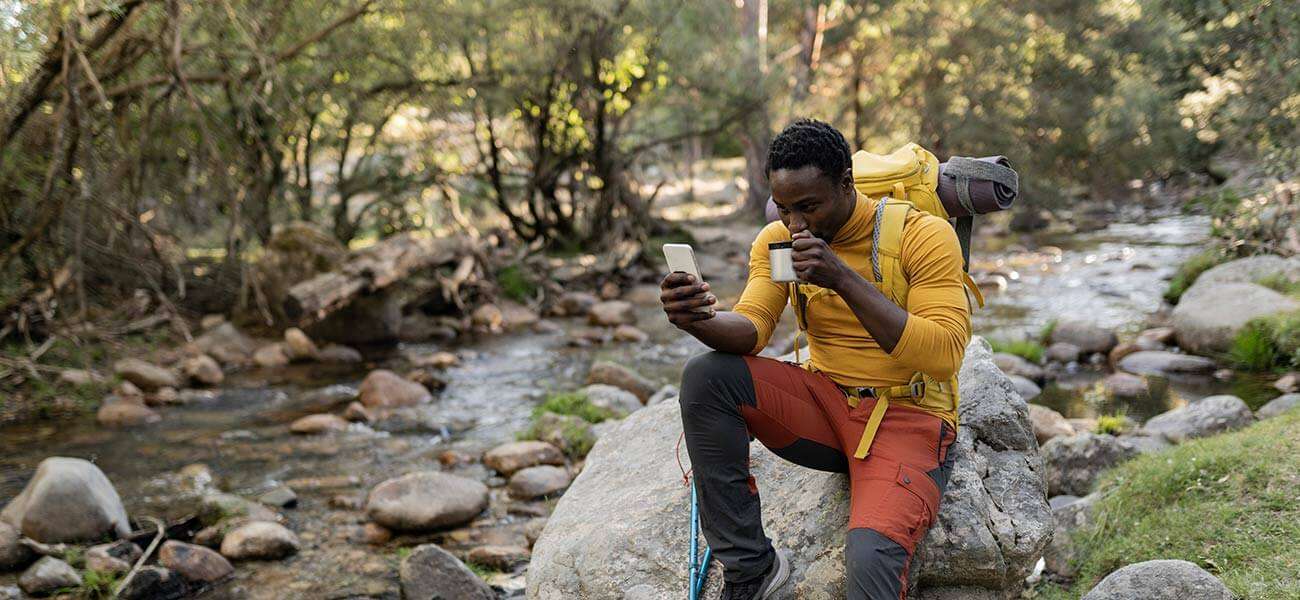 Man on hiking trail checks his phone messages - take your home calls with you wherever you go with Astound