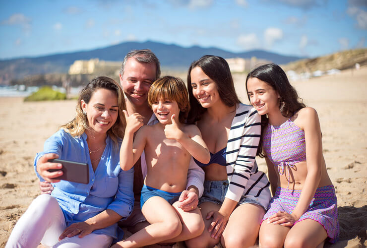 Family takes a selfie at the beach - beat the heat with Astound's Summer Entertainment Guide