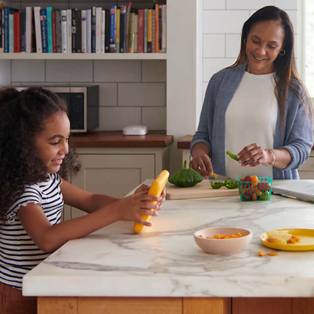 girl uses device connected through eero as mom makes dinner