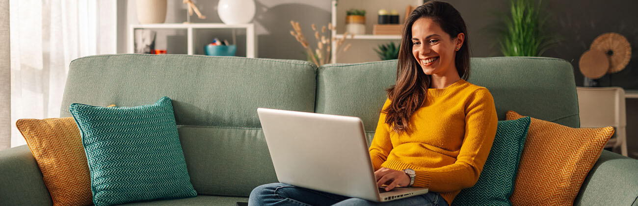 Woman on couch browsing a laptop