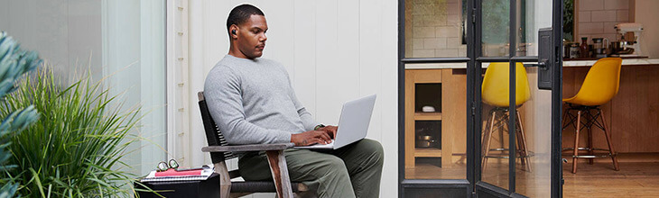 man sits on his patio using a laptop