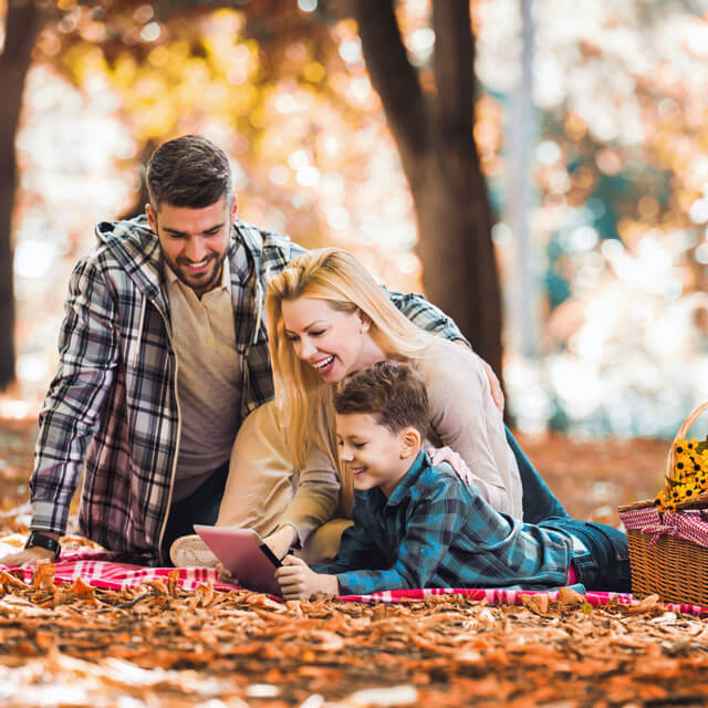 Dad, Mom and son watching favorite shows on a fall picnic