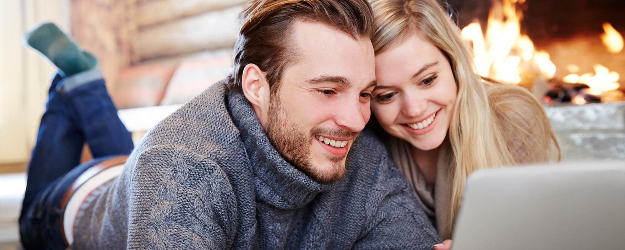 cozy couple watching streaming shows in front of crackling fireplace in the winter