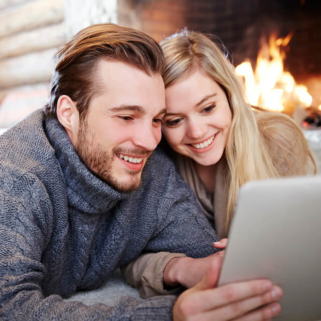 cozy couple watching streaming shows in front of crackling fireplace in the winter