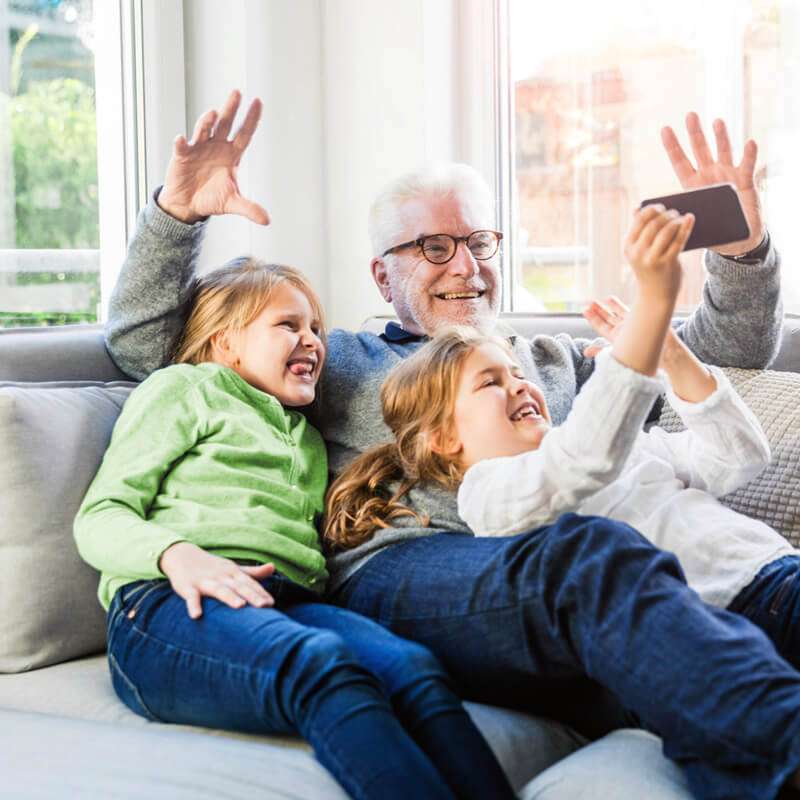 Grandfather takes selfie with kids while lounging at home