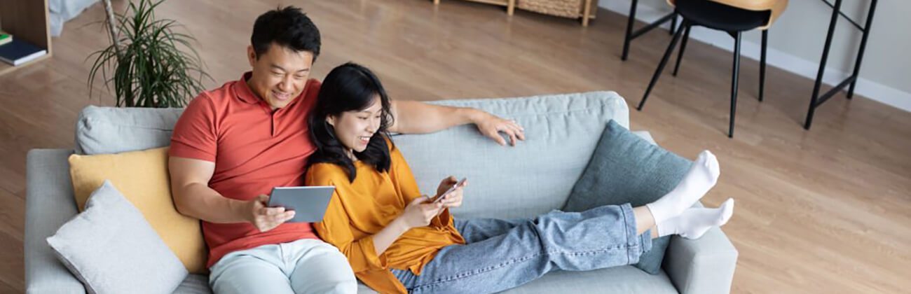 couple looking at their electronics on a couch