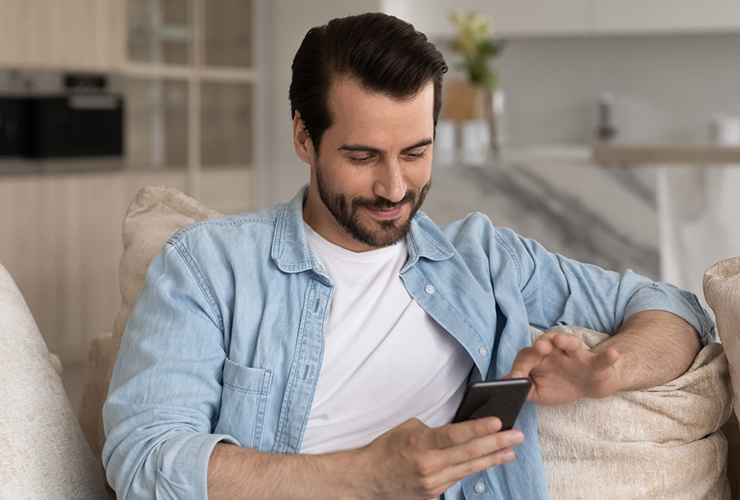 man sitting on the couch scrolling his phone